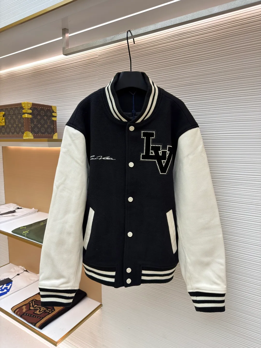 LOUIS VUITTON checkerboard embossed genuine leather and wool baseball jersey ●Original version: 51000 purchased and developed ●Item number: 1680926-i15 ●Fabric: genuine leather wool fabric ●Technology: embroidery ●Version: fitted version ●Weight: about 1770 grams ●Size: 44-46-48-50 ●Description: The fabric is made of 80% wool, with a weight of 750g. It is made of newly sheared wool and is dyed in reactive black in the vat. The colored cloth is bristle process. After brushing 5 times and washing 6 times, the fluffy surface fluff is trimmed flat, and the surface of the fabric appears fluffy. It has a hollow three-dimensional fluffy effect. You can feel the elasticity of the fabric when you touch and press it with your hands. The newly sheared wool yarn is long-fiber and is not easy to pill after shearing. The front and back panels are embroidered with Tajima embroidery machines imported from Japan. The nylon material is super matte and the tatami stitch method is multi-layered. Overlapping thread embroidery, the front chapter is made of viscose yarn, three-dimensional toothbrush embroidery, the mold is opened to determine the pile height and the suede is smoothed by hand, using acrylic round bubble beads, the surface of the bubble beads is sprayed three times, the base paint is latex paint, and the middle layer is sprayed with pearls Pearl white paint, the outer layer is sprayed with translucent glossy paint, the translucent bright white effect is completely comparable to that of mother-of-pearl. There are a total of 154 beads in the chapter. Each bead is dusted and positioned to ensure that it is flush with the edge of the chapter. The visual effect is not obtrusive. The two sleeves are made of water Made of dyed cowhide. Compared with spray-painted cowhide, there is nothing attached to the surface of water-dyed cowhide. Pure water-based dyes are continuously stirred in the tank to naturally color. During the period, samples are taken to compare the color of the Y-version sleeves according to the degree of coloring. When the colors are basically the same, they can be washed and dried naturally to produce the finished product. The thickness of the finished leather is 12mm. The embossing is made of a large-size aviation aluminum plate material mold. All the flowers are pressed according to the code positioning. An electric hydraulic control system is used, and the constant temperature and timing are automatically operated. The small sleeve logo is embossed separately from the small mold. It is pressed by electromagnetic pulse pressure and heating. After the sleeves are cut and embossed, the leather base is all shoveled to a thickness of 8mm. The leather thickness is reduced and the hand feels softer and closer to the body. The diamond-shaped plaid embossing on the surface causes an anti-skin phenomenon due to the thinning of the leather base. The pattern will naturally increase from the deep base state. Lightened, the diamond check pattern and the leather pebbles form a visually invisible effect. It is matched with cupro + cotton blended lining, the ribs are made of combed cotton yarn, and the horizontal loom imported from Taiwan has inter-color jacquard. It is matched with a custom-made molded aluminum alloy material with a logo spray-painted four-button buckle.
